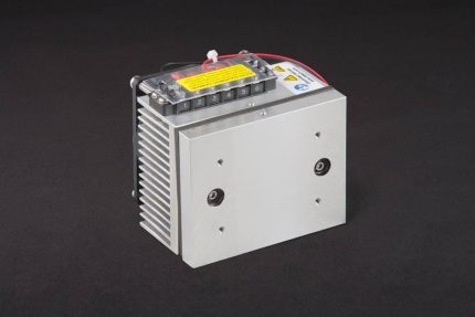 Three-quarter view of thermoelectric cold plate cooler/heater. Cooled aluminum plate on the front, waste heat exhausted to fins on back. Fins are fan cooled. The fan air enters on the middle back and exhausts on sides. Operates on 12 volts DC and removes 30 watts of heat at a 0°C temperature difference relative to ambient.