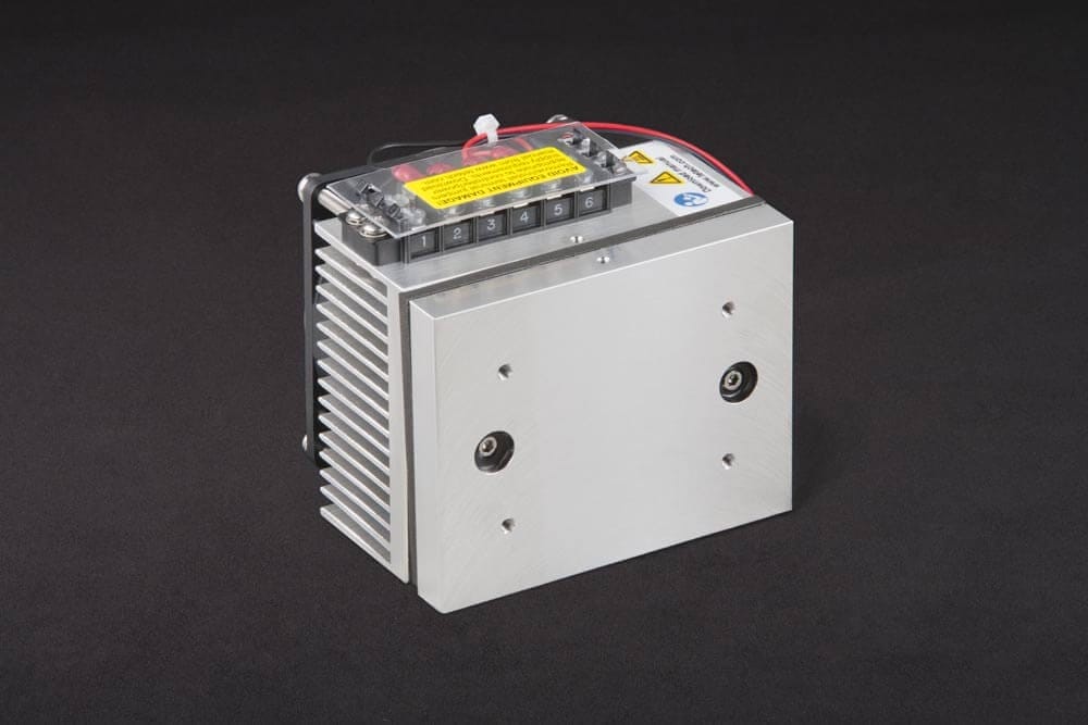 Three-quarter view of thermoelectric cold plate cooler/heater. Cooled aluminum plate on the front, waste heat exhausted to fins on back. Fins are fan cooled. The fan air enters on the middle back and exhausts on sides. Operates on 12 volts DC and removes 30 watts of heat at a 0°C temperature difference relative to ambient. Can heat to 100°C without damaging the cooler.