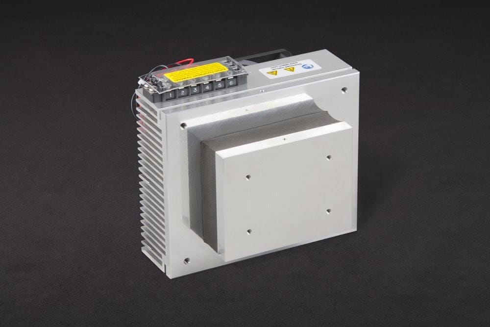 CP-036 Three-quarter view of thermoelectric cold plate cooler/heater. Cooled aluminum plate on the front, waste heat is exhausted to fins on back. Fins are fan cooled. The fan air enters on the middle back and exhausts on sides. Operates on 12 volts DC and removes 32 watts of heat at a 0°C temperature difference relative to ambient. An internal extender block improves the heat pumping capacity at larger temperature differences.